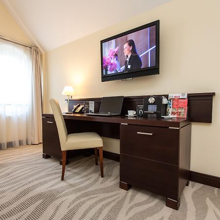 Radisson Blu Hotel, Гданск Екстериор снимка The photo depicts a corner of a room featuring a stylish desk with a chair and a television mounted on the wall above. The desk has various items on it, possibly including a telephone, clock, and some decorative elements or stationery. There is a lam