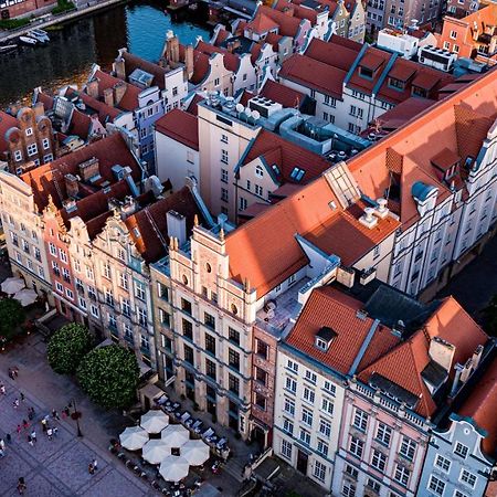 Radisson Blu Hotel, Гданск Екстериор снимка The photo shows a bird's-eye view of a picturesque urban area, likely in a historical city. It features a cluster of buildings with a mix of architectural styles, characterized by colorful facades and predominantly red rooftops. The buildings seem to
