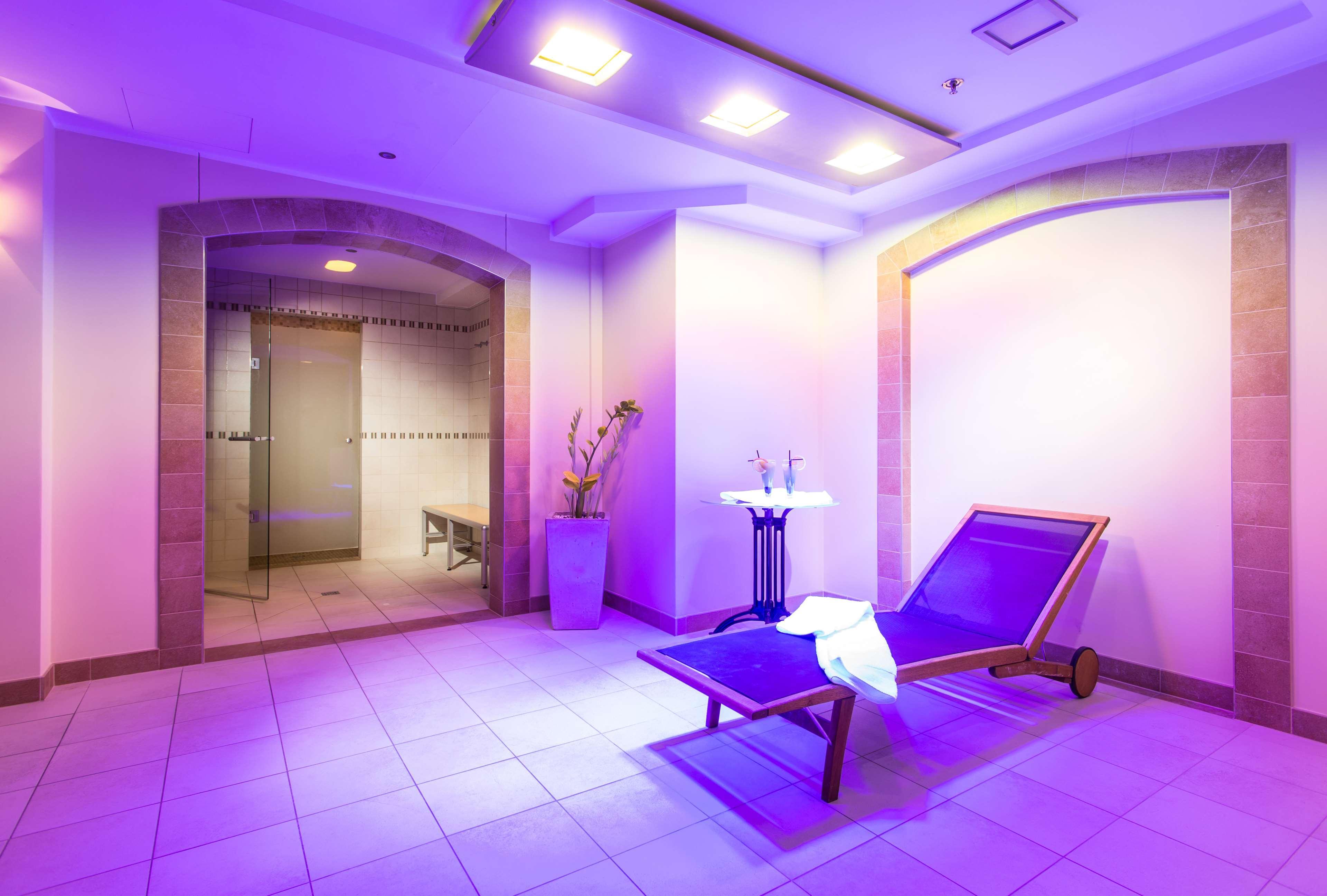 Radisson Blu Hotel, Гданск Екстериор снимка The photo shows a serene spa-like environment. There is a long, reclining lounge chair positioned in a softly lit area, with purple lighting creating a calming ambiance. Nearby, a small table holds two glasses, suggesting a place for relaxation. On t
