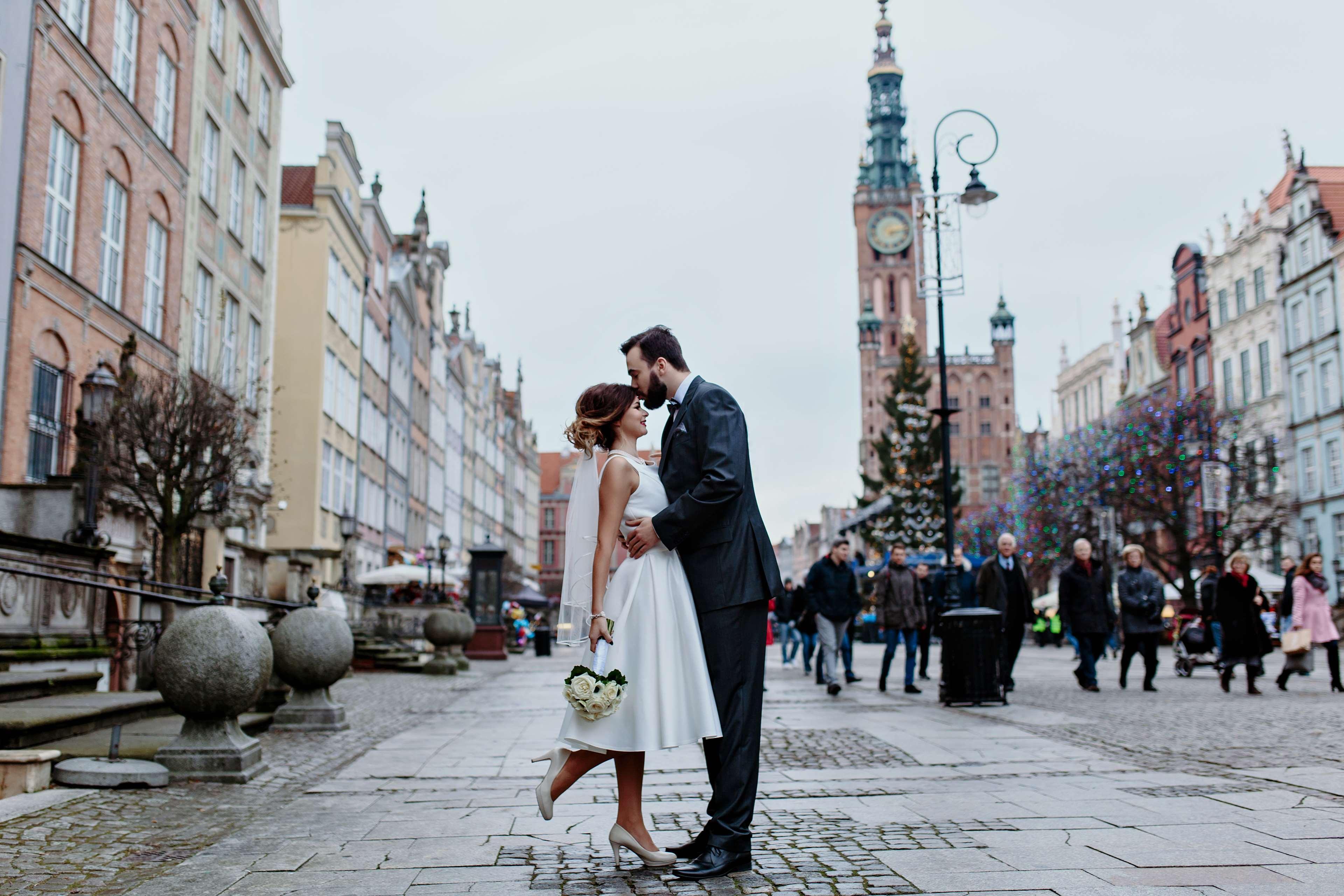 Radisson Blu Hotel, Гданск Екстериор снимка The photo depicts a joyful moment between a couple in a romantic embrace on a lively street. The woman is wearing a white wedding dress, and the man is dressed in a smart suit. They appear to be celebrating their love, possibly on their wedding day. 