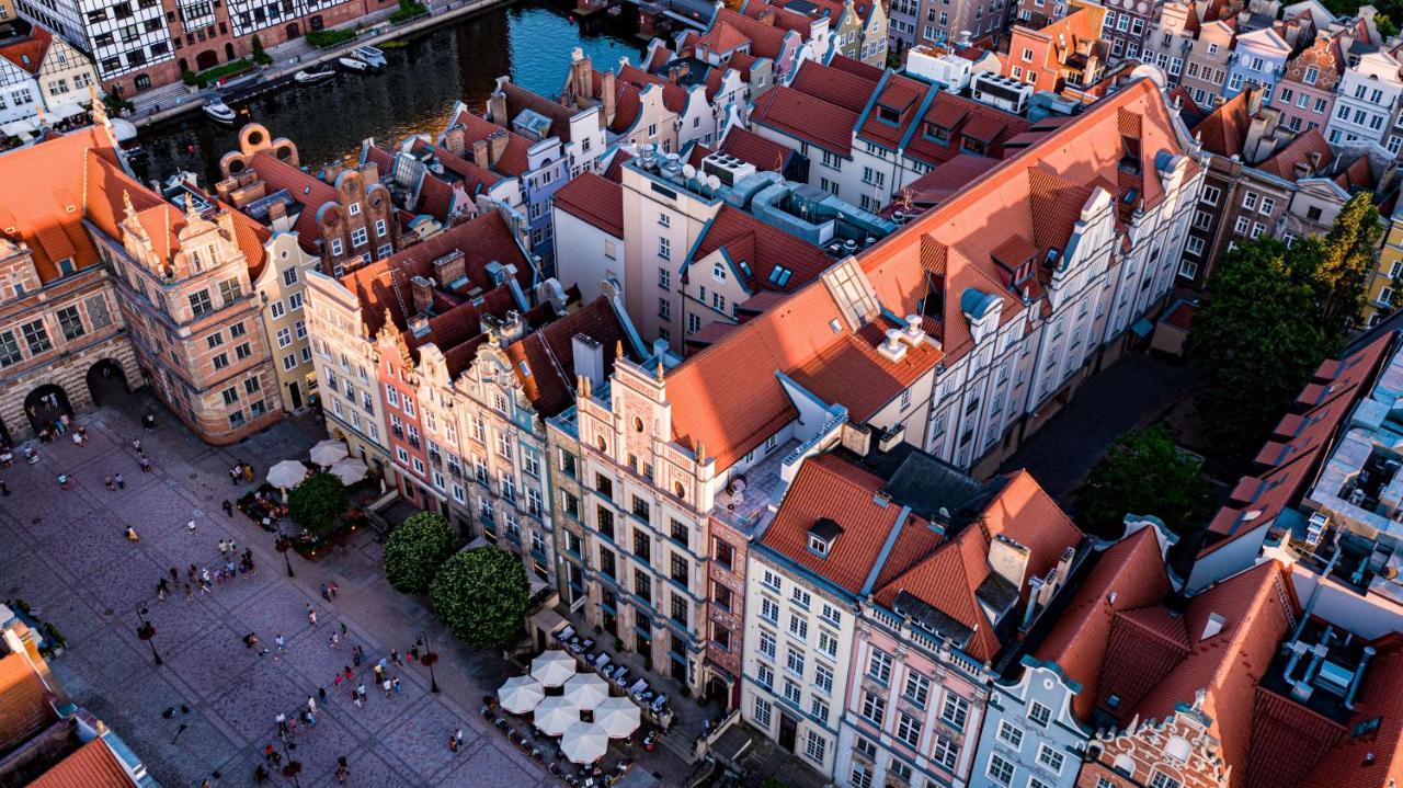 Radisson Blu Hotel, Гданск Екстериор снимка The photo shows a bird's-eye view of a picturesque urban area, likely in a historical city. It features a cluster of buildings with a mix of architectural styles, characterized by colorful facades and predominantly red rooftops. The buildings seem to