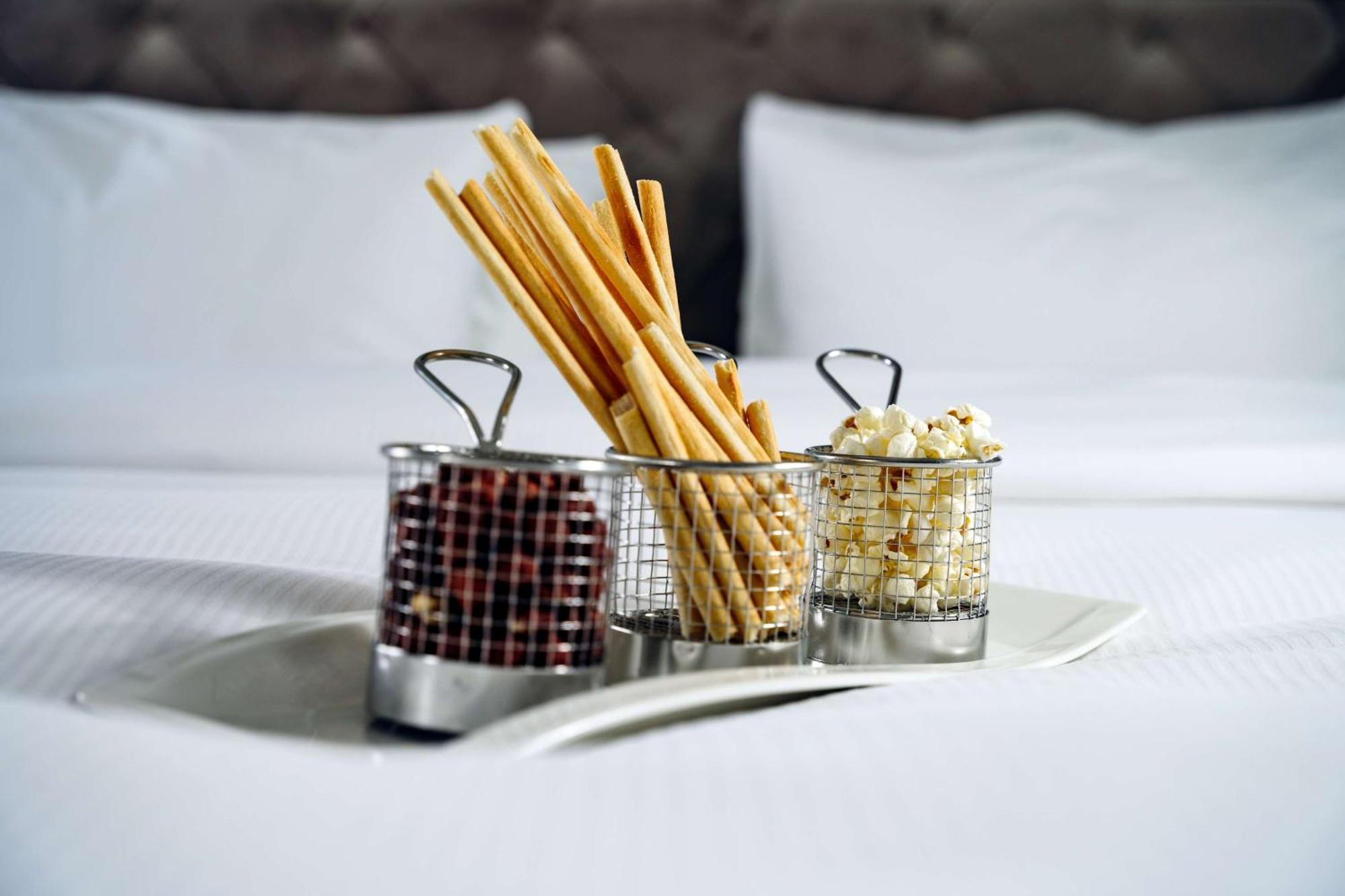 Radisson Blu Hotel, Гданск Екстериор снимка The photo shows a tray with three small metal baskets. Each basket contains a different type of snack. 

1. The first basket holds breadsticks, which are long and thin, arranged upright.
2. The second basket contains what appears to be chocolate-cove