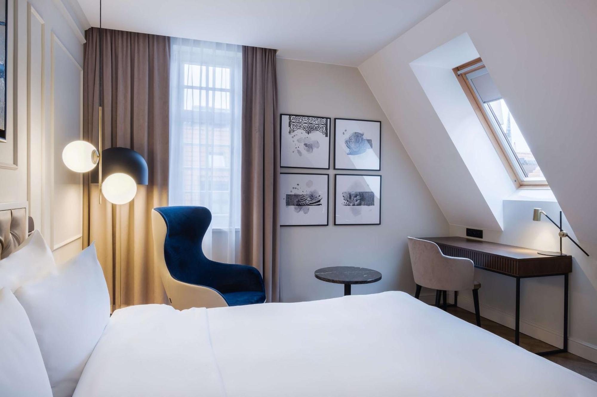 Radisson Blu Hotel, Гданск Екстериор снимка The photo shows a cozy hotel room featuring a modern design. The room has a double bed with a white duvet, and a large window with sheer curtains that allows natural light to filter in. On the wall opposite the bed, there are several framed artworks.